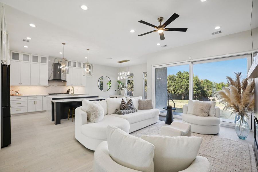 Living area featuring a ceiling fan, light wood-style flooring, and suspended lighting