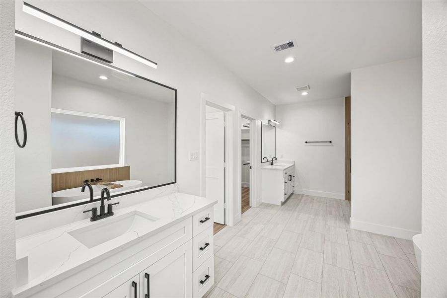 Dual quartz vanities with modern mirrors and designer lighting.