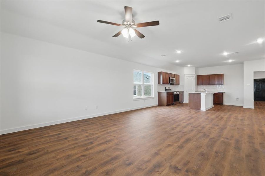 Unfurnished living room featuring dark wood-style flooring, ceiling fan, and recessed lighting Unfurnished living room featuring dark wood-style flooring, ceiling fan, and recessed lighting