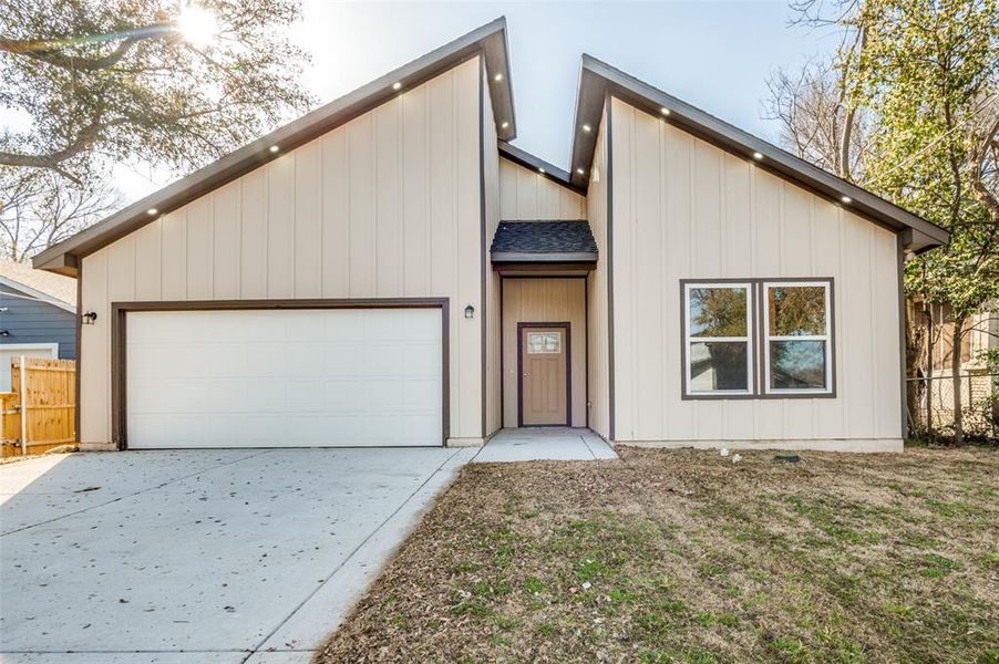 View of front of property with a shingled roof, an attached garage, concrete driveway, and fence