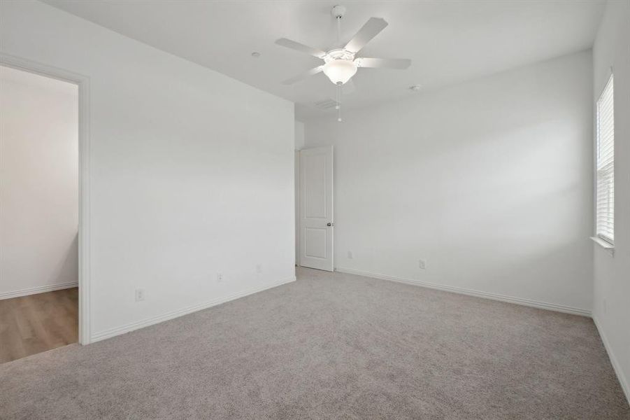 Spare room with ceiling fan, plenty of natural light, and light colored carpet