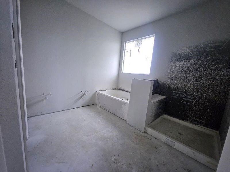 Bathroom under construction featuring a built-in bathtub, a shower pan, and a window Bathroom under construction featuring a built-in bathtub, a shower pan, and a window