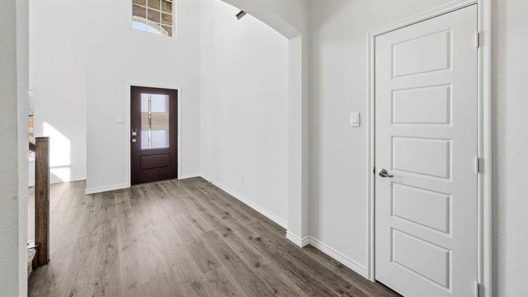 Entrance foyer featuring arched walkways, a high ceiling, and wood finished floors