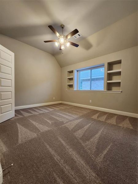 Unfurnished room featuring ceiling fan, carpet flooring, and built in features