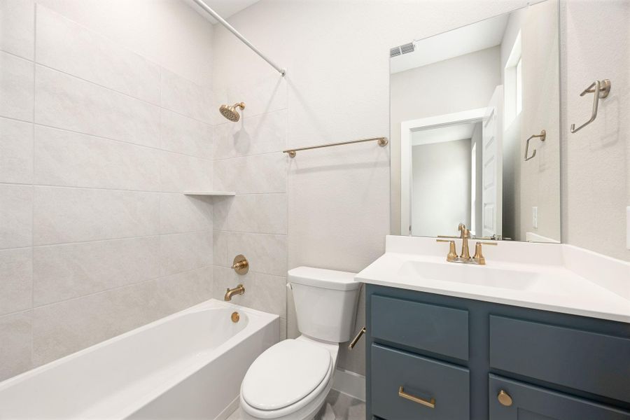 The en-suite bath features a tub/shower combo, a single-sink vanity, and designer gold fixtures throughout. The en-suite bath features a tub/shower combo, a single-sink vanity, and designer gold fixtures throughout.