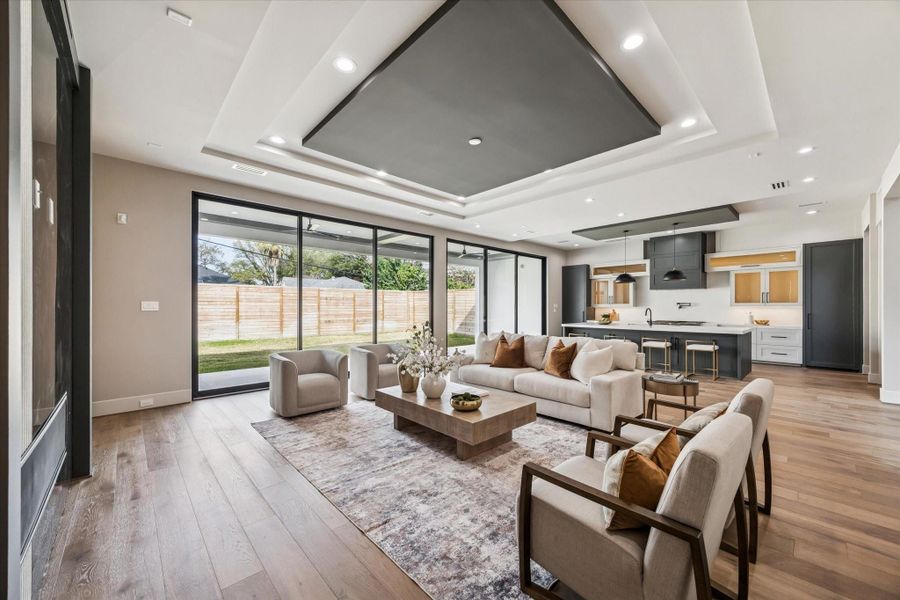A wall of glass sliding doors floods the space with natural light and connects to the outdoors, while rich oak flooring flows effortlessly into the open kitchen, creating a perfect setting for both entertaining and everyday living.