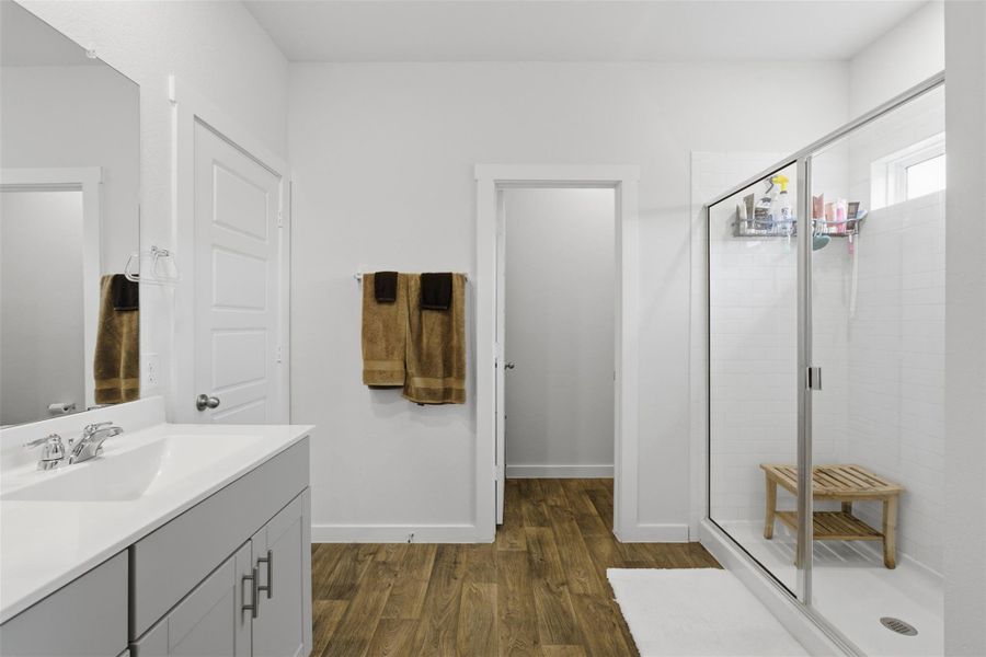 Full bathroom featuring a stall shower, dark wood-style floors, and vanity