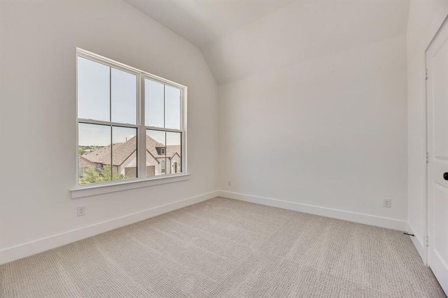 Empty room with light carpet and lofted ceiling Empty room with light carpet and lofted ceiling