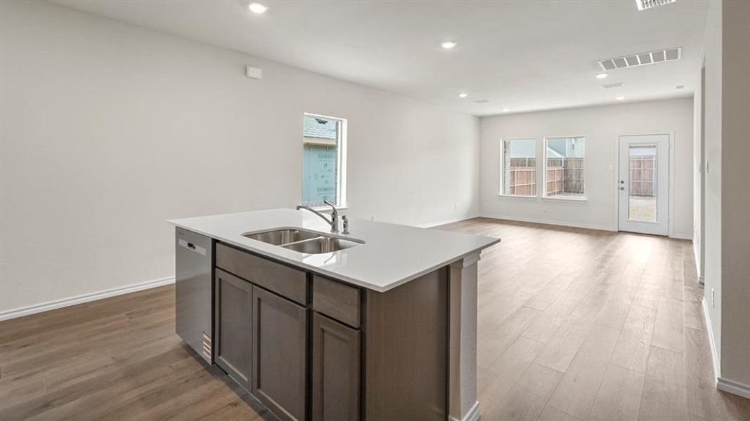 Kitchen island featuring a double-basin sink, stainless steel faucet, and integrated dishwasher
