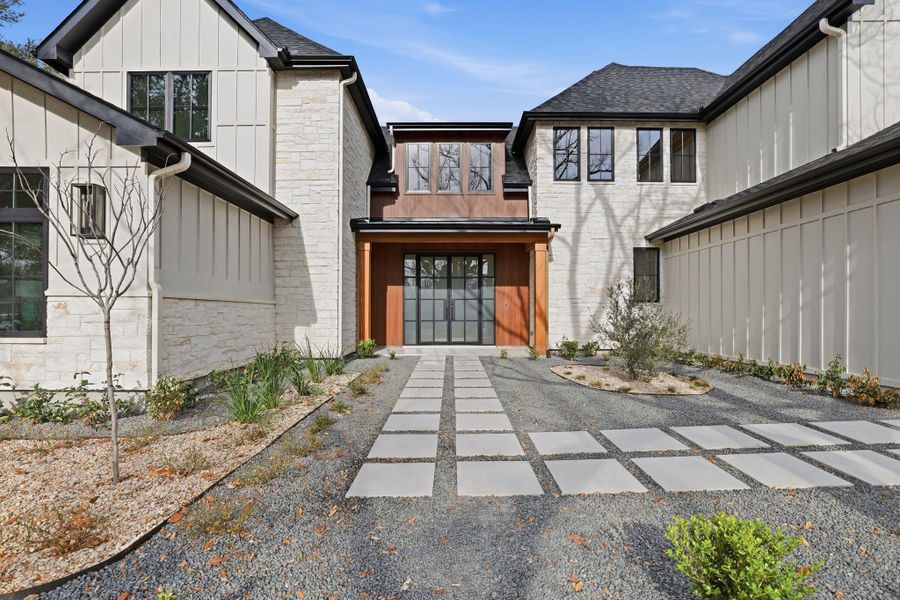 Doorway to property featuring stone siding, board and batten siding, and a shingled roof