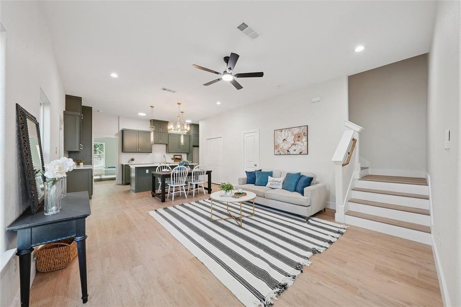 Living area with a chandelier, stairway, light wood finished floors, recessed lighting, and ceiling fan