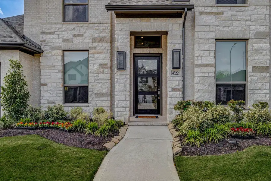 Modern stone facade with a welcoming entrance, framed by manicured landscaping and vibrant flower beds. The large windows allow ample natural light, enhancing the house's curb appeal. Modern stone facade with a welcoming entrance, framed by manicured landscaping and vibrant flower beds. The large windows allow ample natural light, enhancing the house's curb appeal.