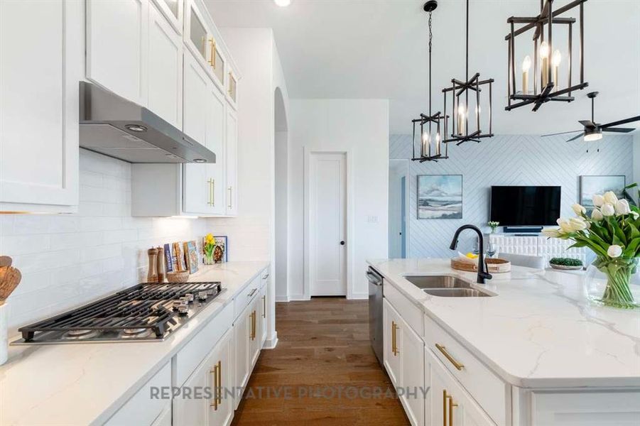 Kitchen with light stone counters, white cabinetry, dark wood-style floors, and decorative light fixtures Kitchen with light stone counters, white cabinetry, dark wood-style floors, and decorative light fixtures
