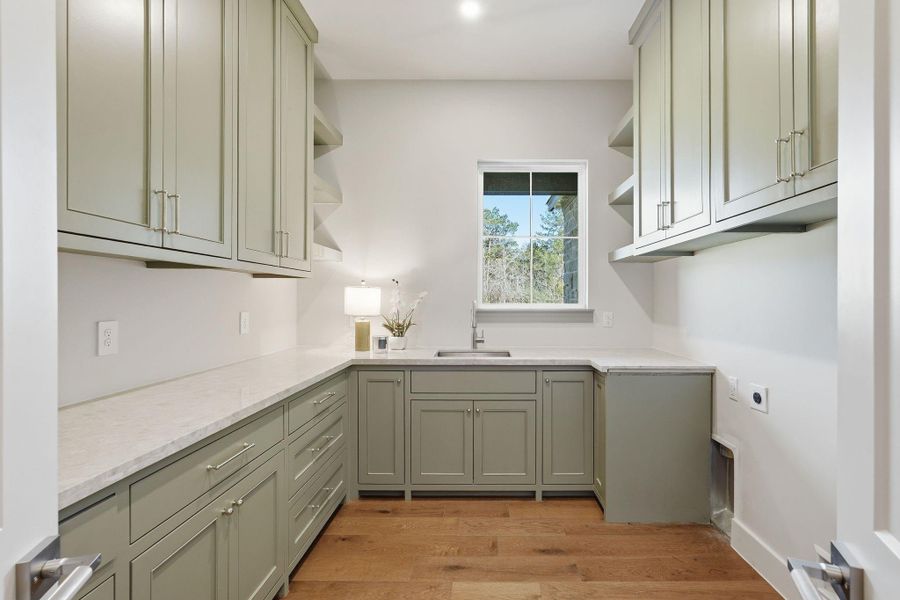 Next-level utility room featuringextensive custom cabinetry,oversized counters, and sink.