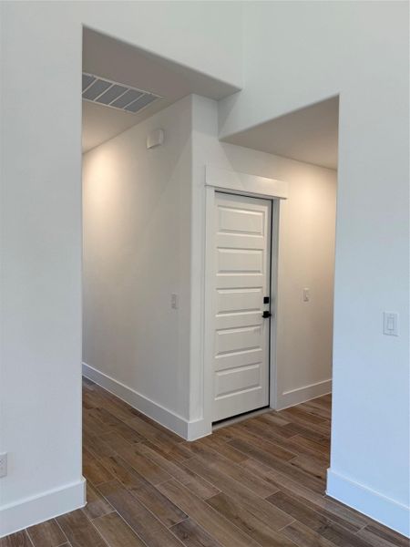 Corridor with dark wood-type flooring and baseboards