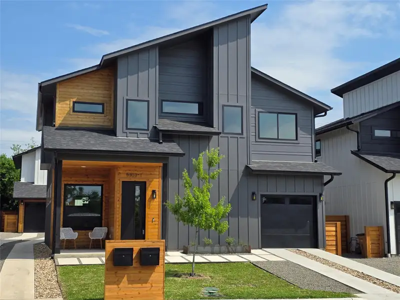 Modern home with board and batten siding, a shingled roof, and a garage Modern home with board and batten siding, a shingled roof, and a garage
