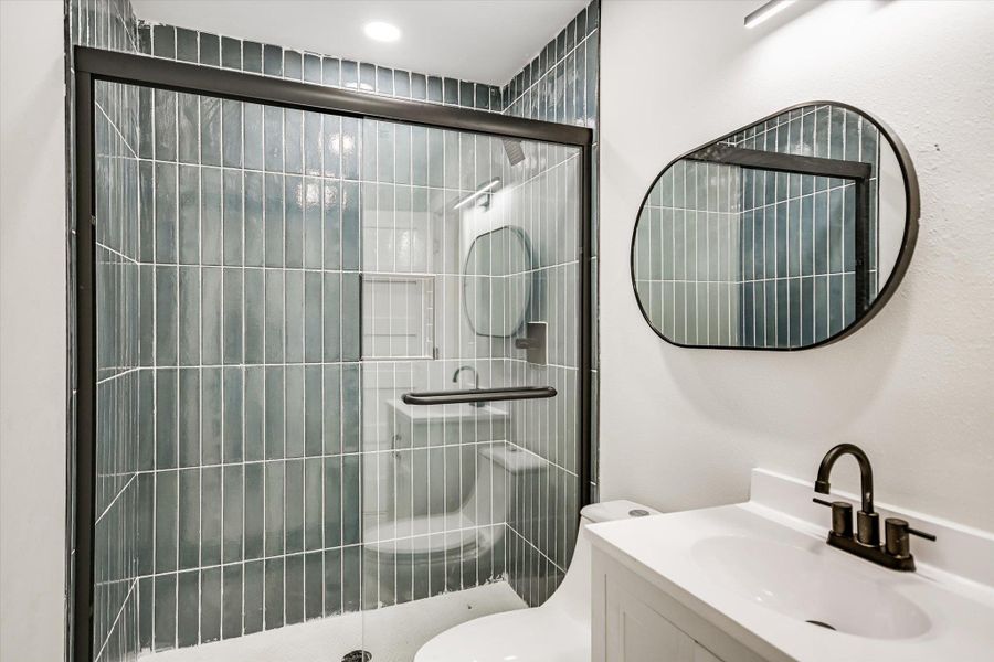 A sleek shower enclosure with vertical subway tiles complements the minimalist vanity in this well-appointed bathroom.