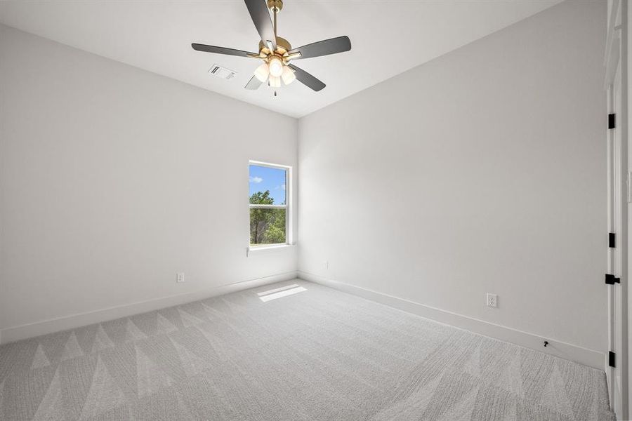 Room featuring light gray patterned carpet, white walls, a single window, and a ceiling fan with integrated lighting