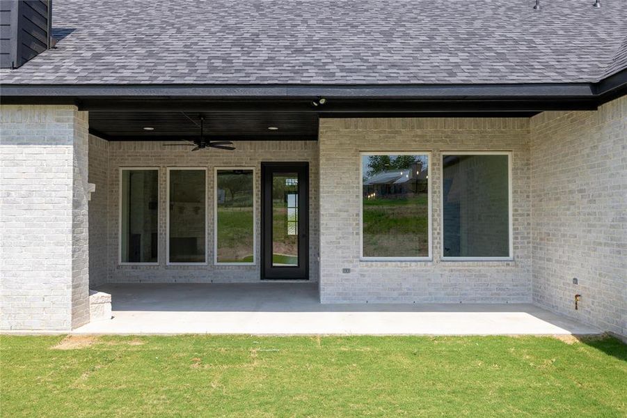 View of exterior entry featuring a yard, ceiling fan, and a patio area