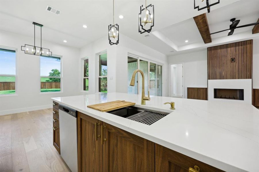 Kitchen featuring plenty of natural light, light hardwood / wood-style floors, decorative light fixtures, and a large fireplace