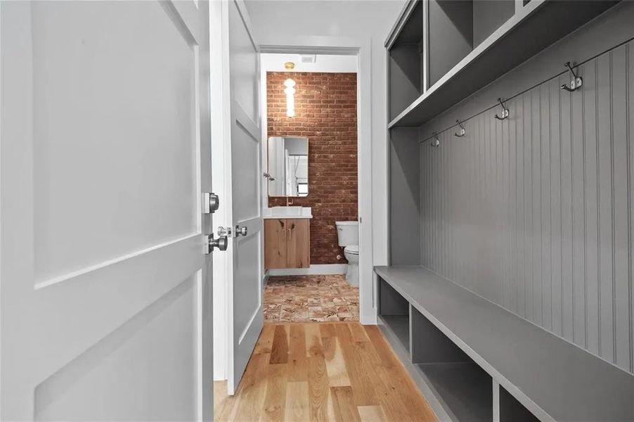Mudroom featuring built-in gray cabinetry with bench seating, wall hooks, and overhead storage Mudroom featuring built-in gray cabinetry with bench seating, wall hooks, and overhead storage