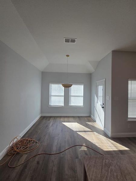 Unfurnished dining area featuring dark wood-style floors and vaulted ceiling