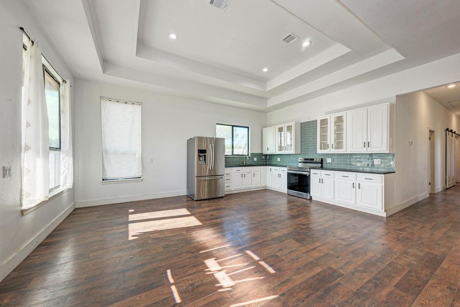 Rich wood floors meet an elegant tray ceiling in this open-concept culinary space.