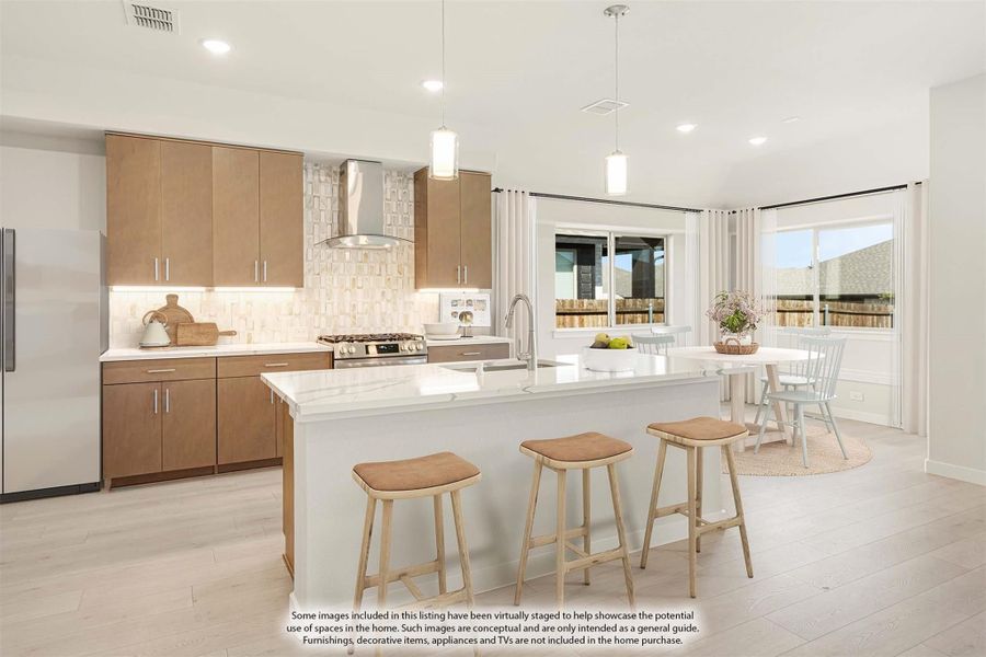 Kitchen with large island, wood cabinets, stainless range hood, and adjacent dining area with natural light
