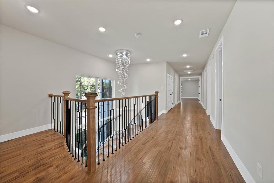 Corridor featuring wood finished floors, a chandelier, recessed lighting, and an upstairs landing Corridor featuring wood finished floors, a chandelier, recessed lighting, and an upstairs landing