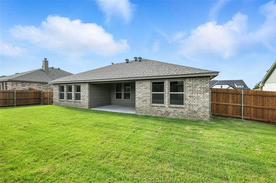 Back of property with brick siding, a patio area, a fenced backyard, and a shingled roof
