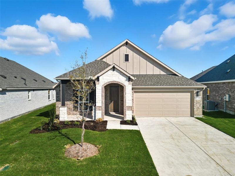 View of front of house with brick siding, board and batten siding, roof with shingles, and a front yard View of front of house with brick siding, board and batten siding, roof with shingles, and a front yard