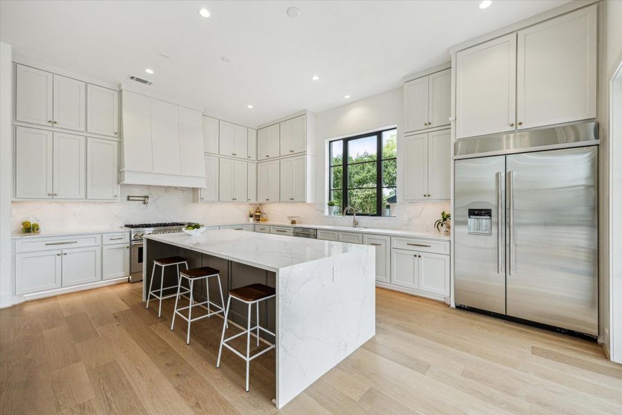 Kitchen has a gorgous island with double quartz waterfall edge and features commercial style appliances including 48" side-by-side refrigerator.