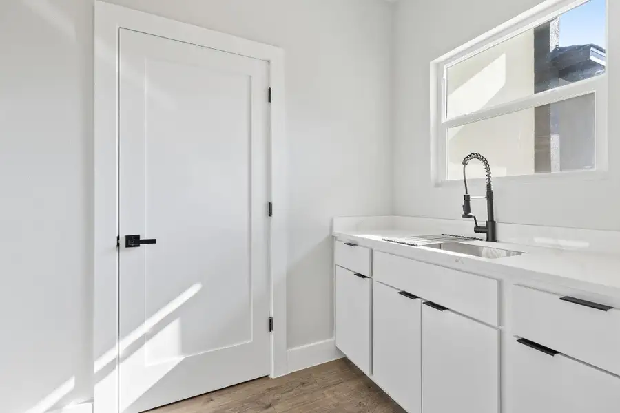 Bar featuring white cabinets, dark wood-style flooring, and light stone countertops