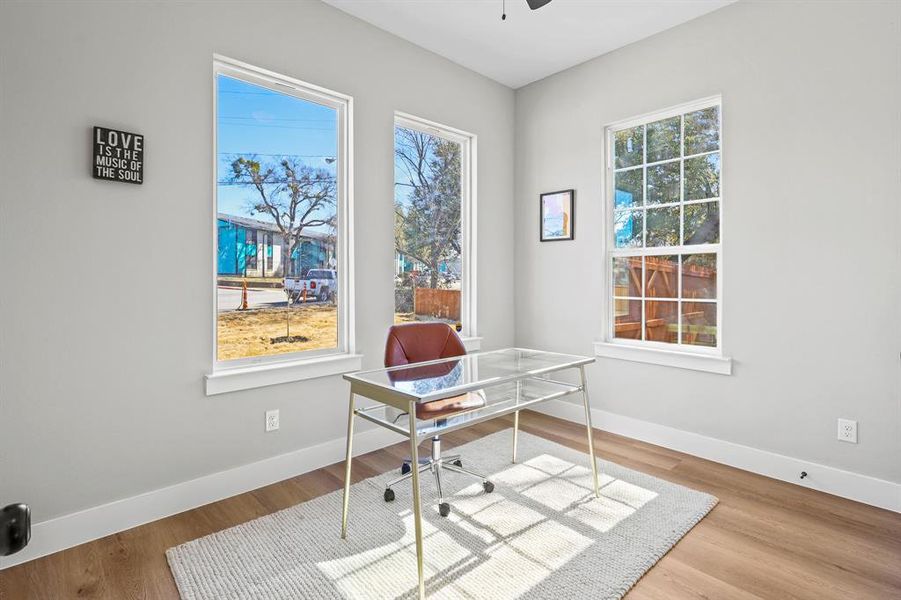 Office space with plenty of natural light, baseboards, ceiling fan, and wood finished floors