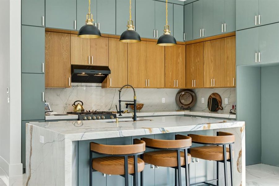 Kitchen featuring light stone counters, a breakfast bar, decorative light fixtures, and decorative backsplash Kitchen featuring light stone counters, a breakfast bar, decorative light fixtures, and decorative backsplash