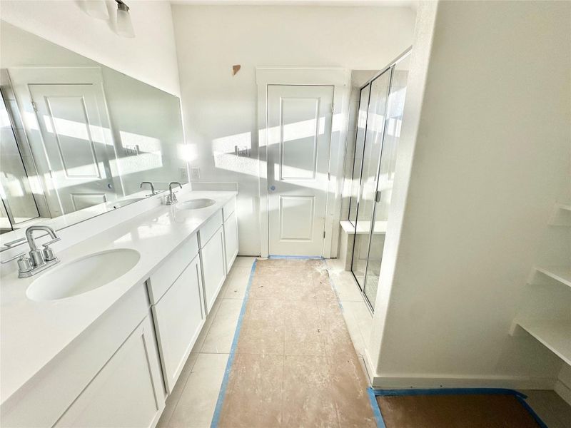Full bath featuring double vanity, a stall shower, and light tile patterned flooring