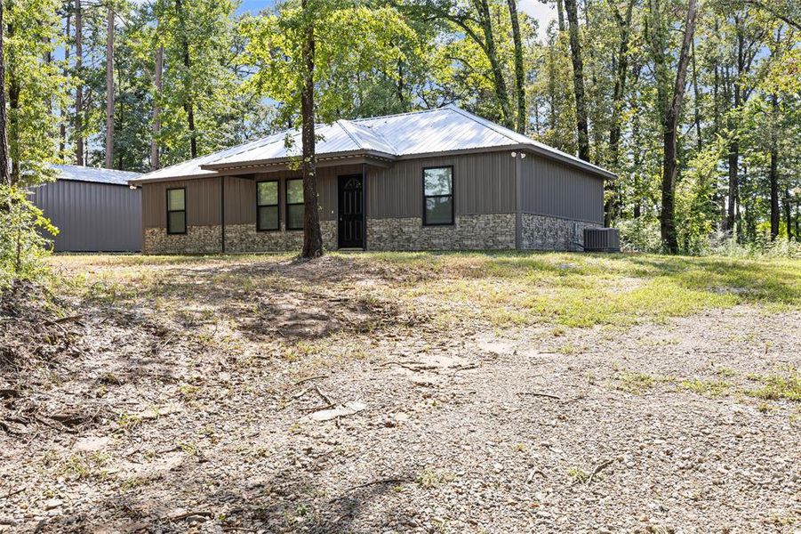 View of front of house featuring stone metal siding and patio View of front of house featuring stone metal siding and patio