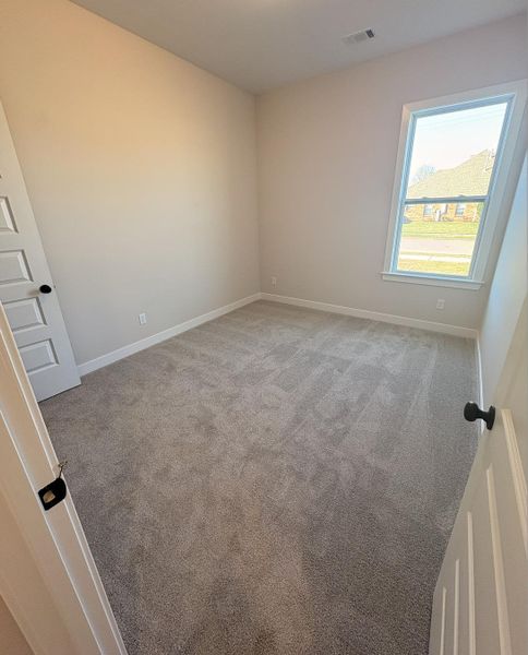 Empty room with light colored carpet and baseboards