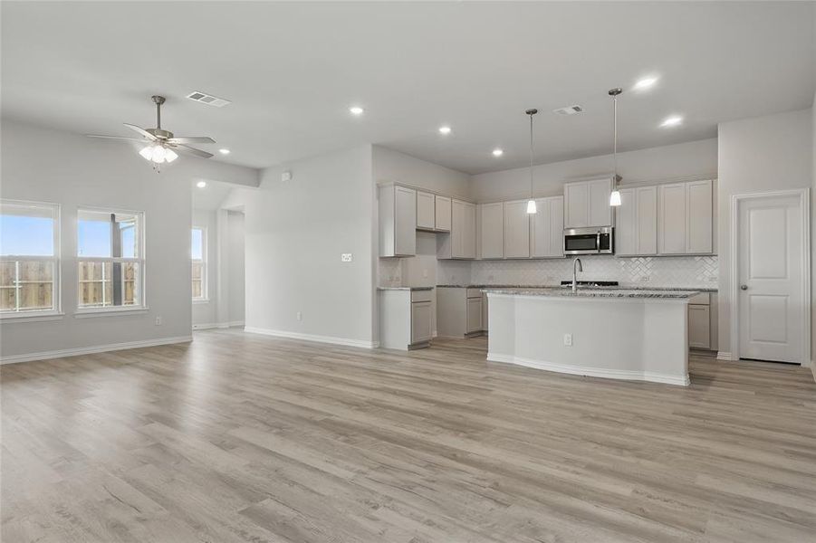 Kitchen with stainless steel microwave, decorative backsplash, recessed lighting, open floor plan, and light wood-style floors Kitchen with stainless steel microwave, decorative backsplash, recessed lighting, open floor plan, and light wood-style floors