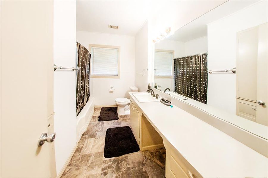 Full bath with vanity, shower / bathtub combination with curtain, and light stone finish floors
