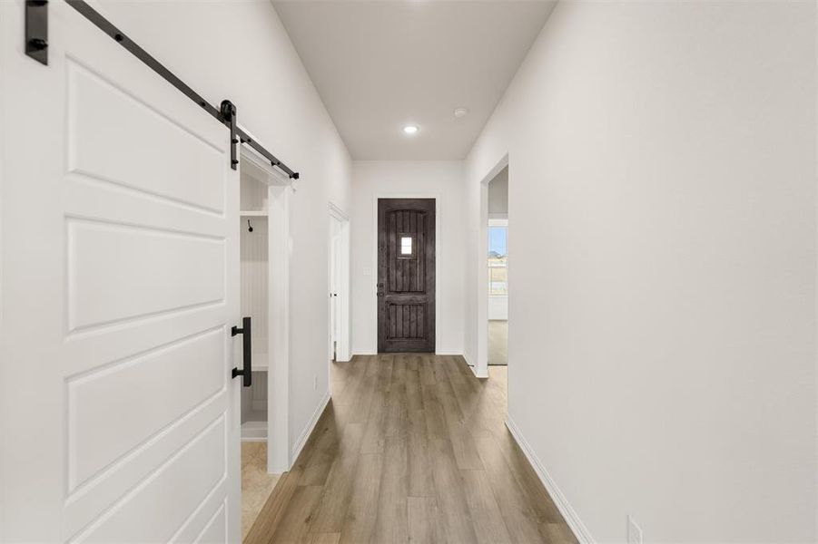 Entryway featuring a barn door, wood finished floors, and recessed lighting