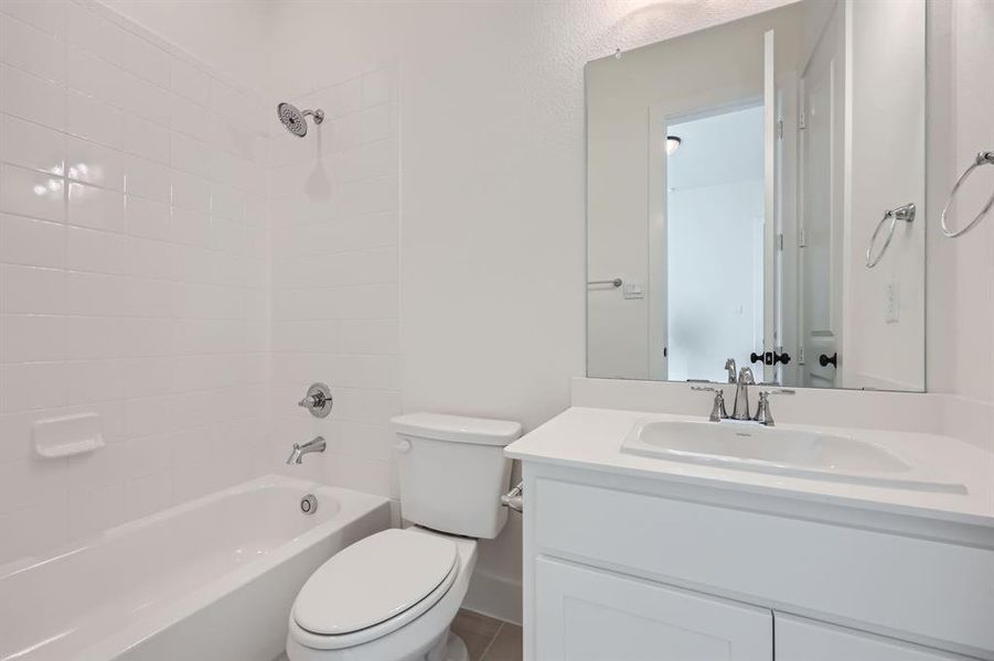 Full bathroom featuring vanity, tiled shower / bath combo, and toilet