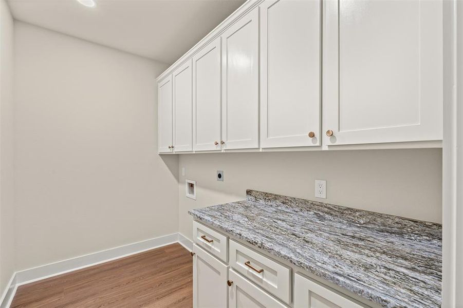 Washroom featuring hookup for a washing machine, cabinet space, light wood-style floors, and electric dryer hookup