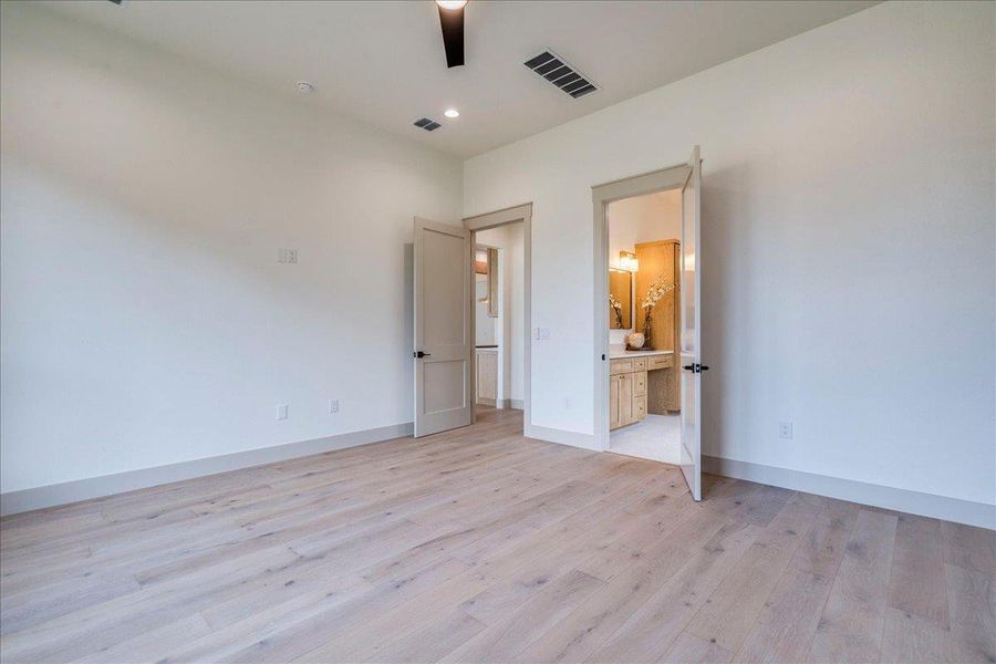 Natural wood flooring complements the serene walls, leading into a well-appointed private bath.