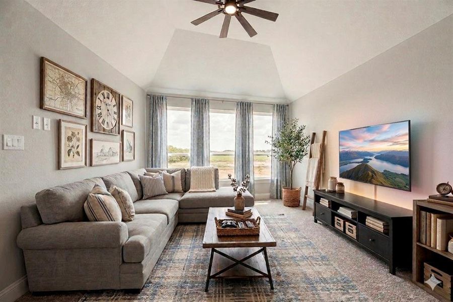 Carpeted living room with a ceiling fan and vaulted ceiling