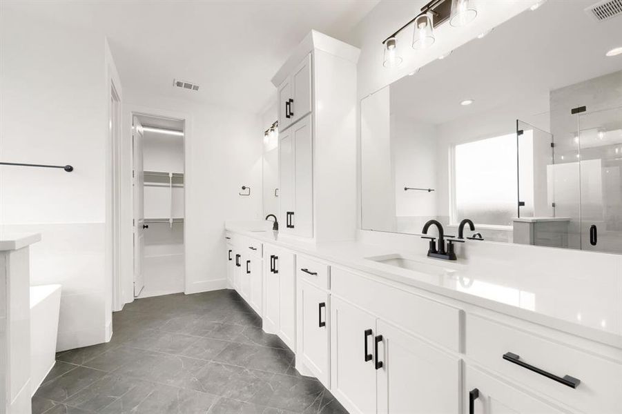 Spacious bathroom featuring a dual vanity with white cabinetry, matte black hardware, and an expansive mirror