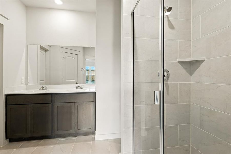 Full bathroom featuring a shower stall, double vanity, and light tile patterned floors Full bathroom featuring a shower stall, double vanity, and light tile patterned floors