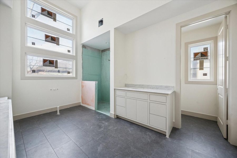 PRIMARY BATHROOM - A bright, spa inspired bath layout features dual vanities with clean lined cabinetry, generous drawer storage, and large format tile flooring for durability and ease. Separate shower and closet access enhance daily flow while maintaining a calm, functional design. -- Construction as of 1/5/26