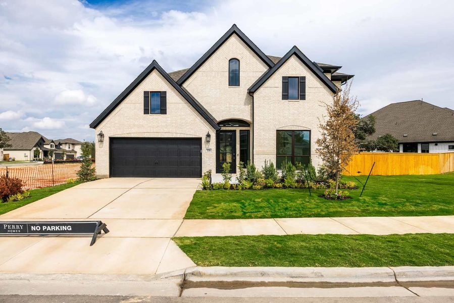 French provincial home with brick siding and driveway