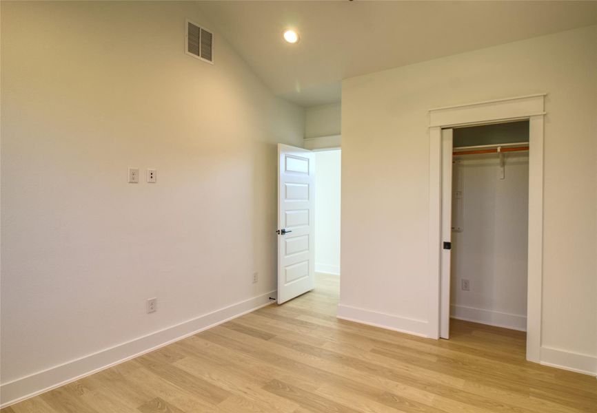 Primary bedroom featuring light wood-style floors, lofted ceiling, a closet, and recessed lighting Primary bedroom featuring light wood-style floors, lofted ceiling, a closet, and recessed lighting